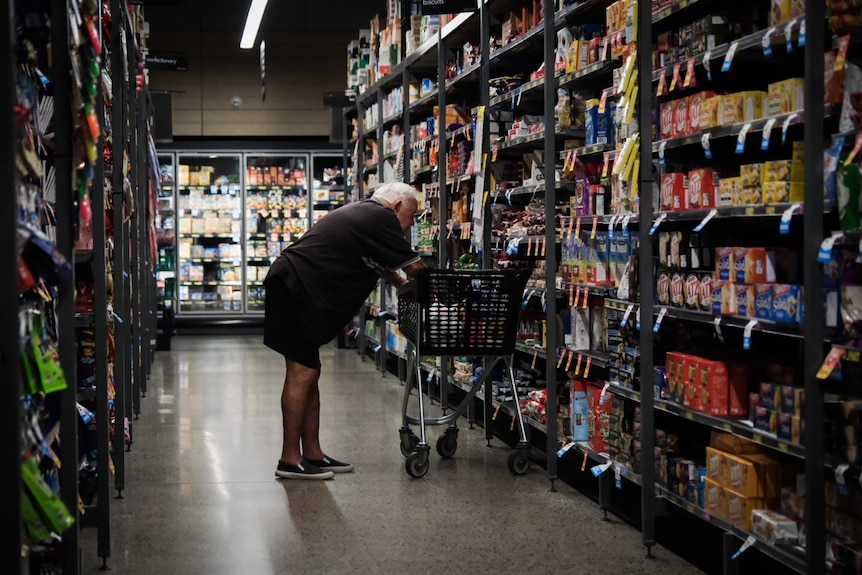 Man leans over shopping trolley in grocery store