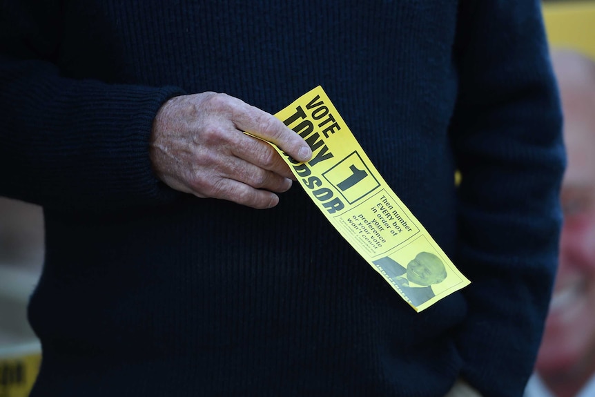 Tony Windsor holds a campaign sticker