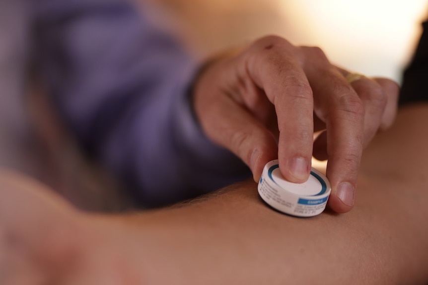 Someone applying a Vaxxas, needle-free vaccine patch to another person's forearm.