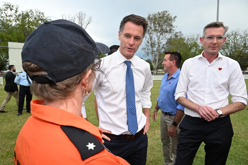 a man speaking with an ses volunteer as another man wearing glasses stands next to him