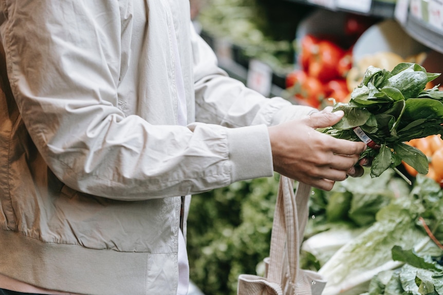 Person picks out a bunch of vegetables at the grocery store