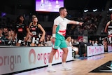 A Super Netball umpire points to the spot where a penalty should be taken.