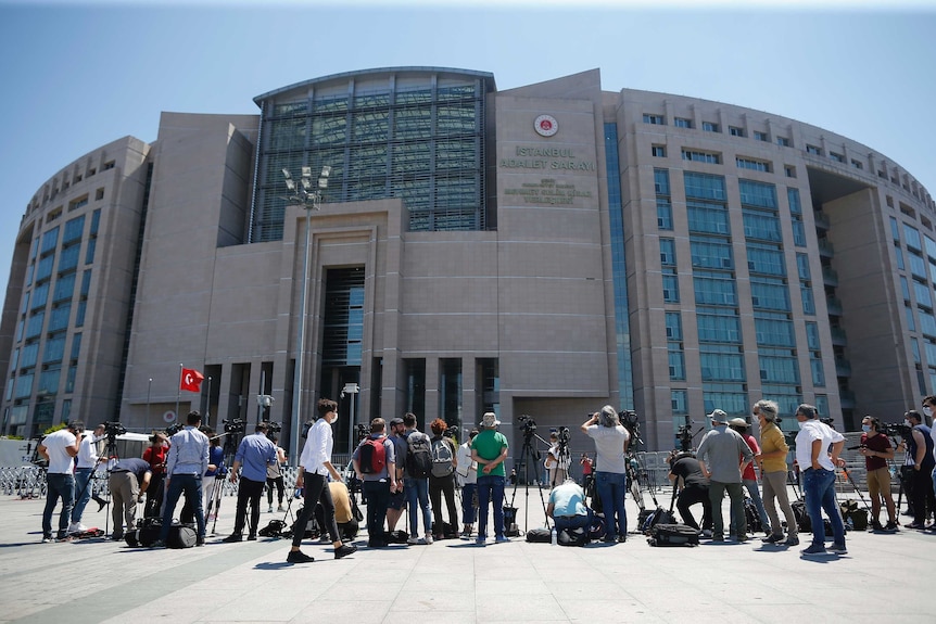 Members of the media, stand outside a court in Istanbul with cameras and tripods.