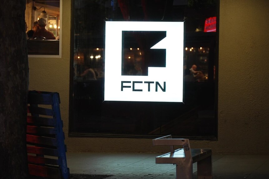 A white sign for Fiction nightclub, pictured at night.