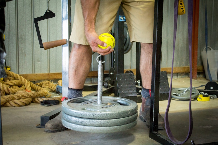 A man lifts a set of weights while standing upright.