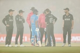 India and New Zealand players stand in the fog