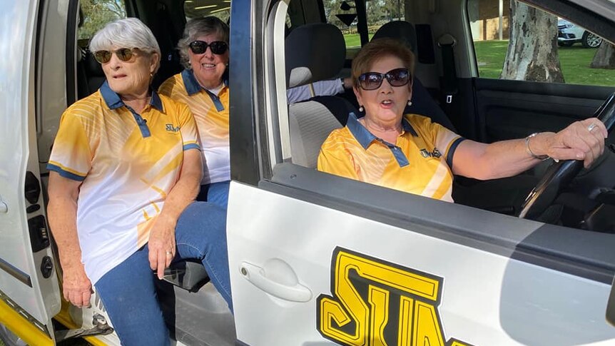 Three women in a van wearing Sunassist polo shirts and sunglasses.