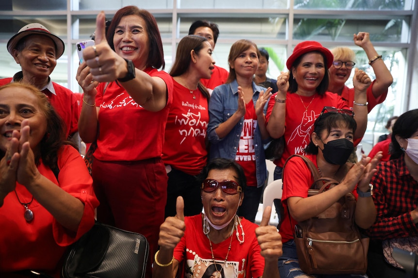 People in red shirts giving thumbs up and cheering 