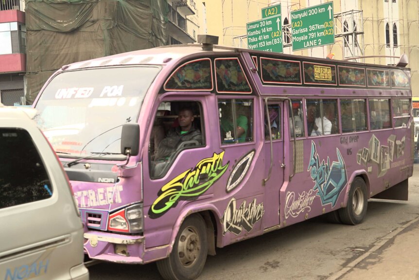 Purple bus decorated with illustrations full with people on an African street