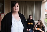 Mandy Weber stands with her daughters Olivia and Mariah sitting eating baked beans in the background.