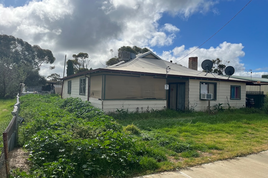 A deserted home in Trayning with overgrown shrub and a car with no registration