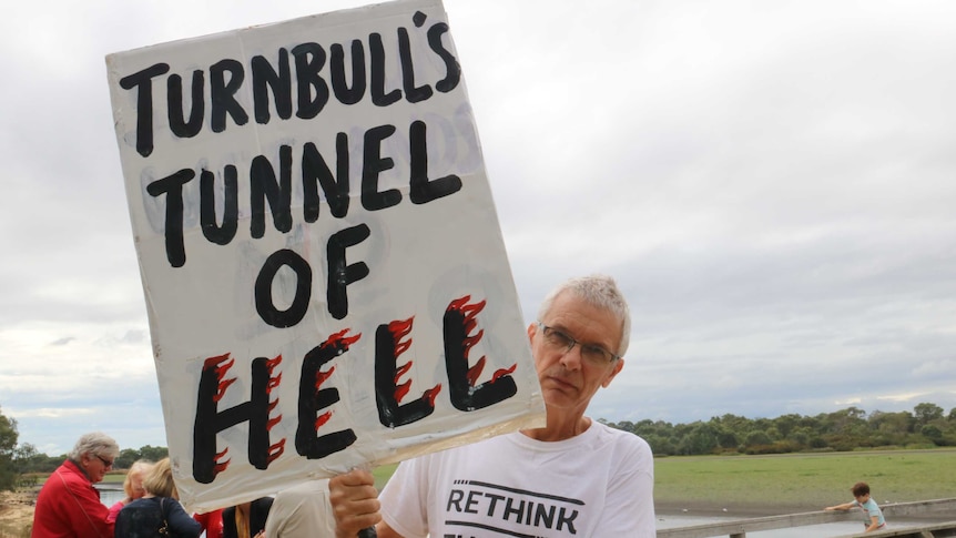 Hilton resident Mark Smith holding a protest sign saying "Turnbull's tunnel of hell".