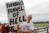 Hilton resident Mark Smith holding a protest sign saying "Turnbull's tunnel of hell".