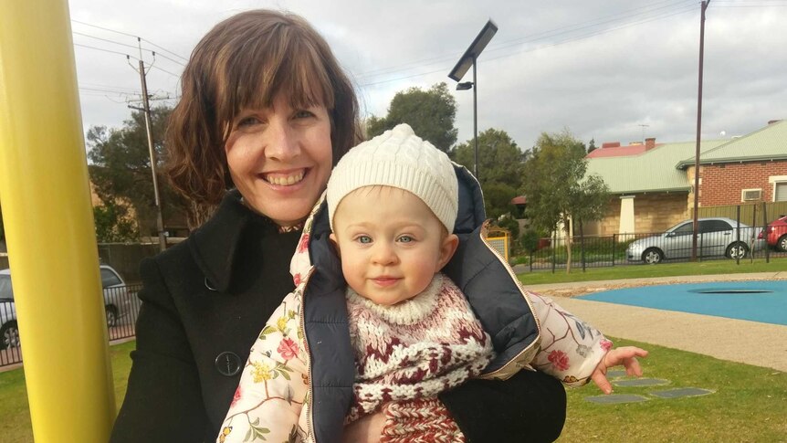 Rachel Ebert holds her daughter Grace at a playground.