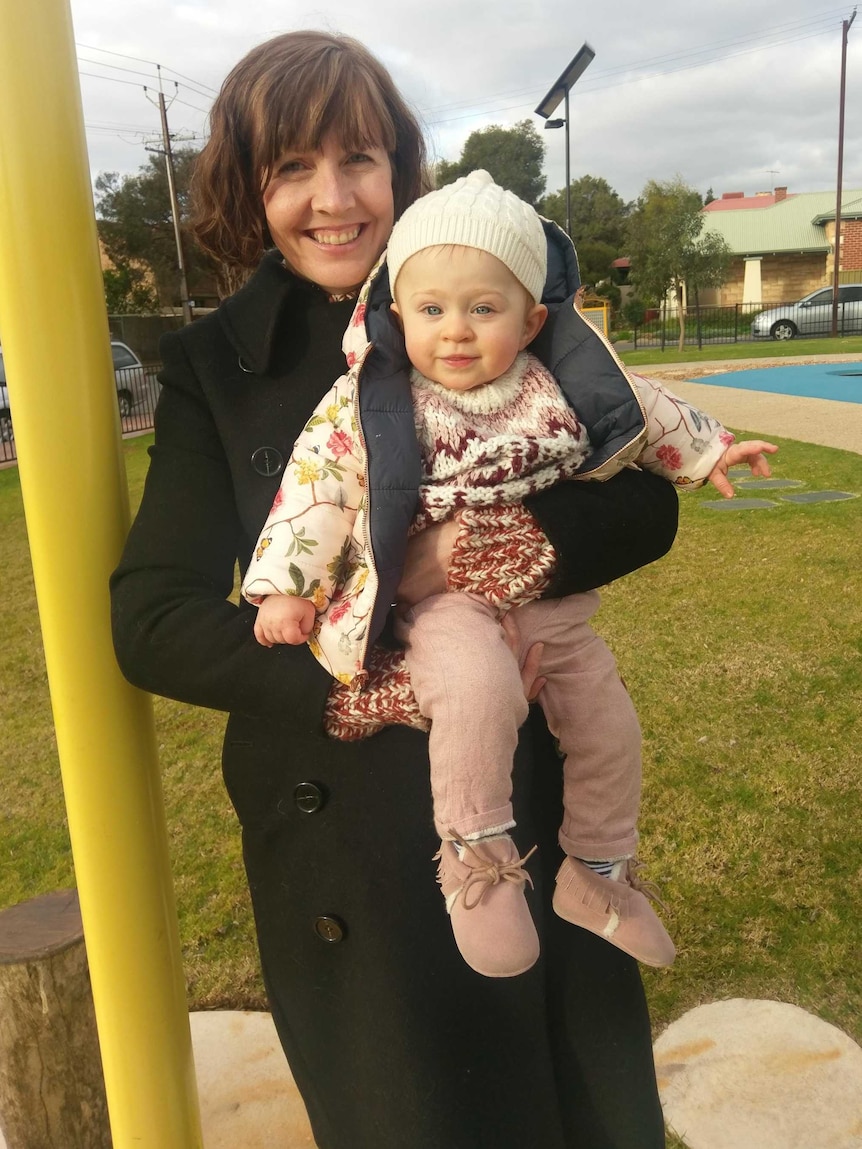 Rachel Ebert holds her daughter Grace at a playground.