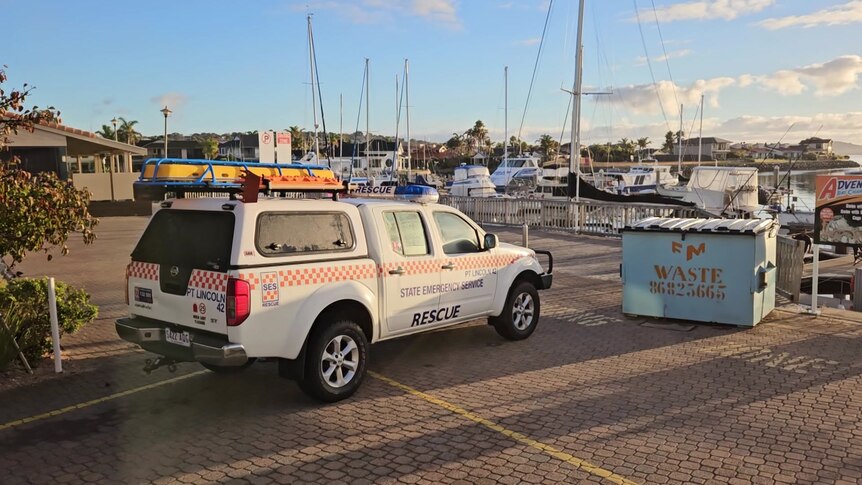 A SES car next to a marina full of boats moored