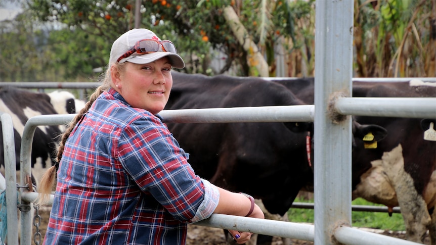 Dairy farmer Laura Burn leans against a cows pen fence.