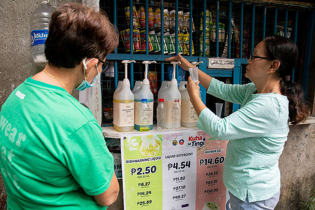 Two women in front of the stall, one of whom is filling a container from a refillable pump bottle.