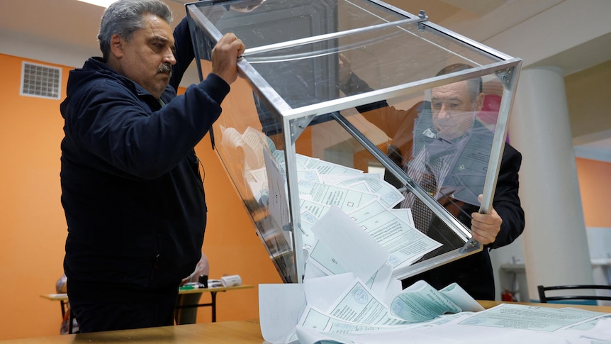 Members of an electoral commission empty a ballot box at a polling station