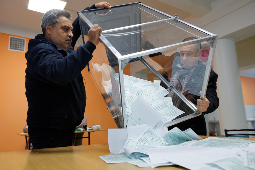 Members of an electoral commission empty a ballot box at a polling station