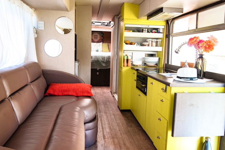 A view of the interior of Kevin's bus, showing a living space, sink and beds.