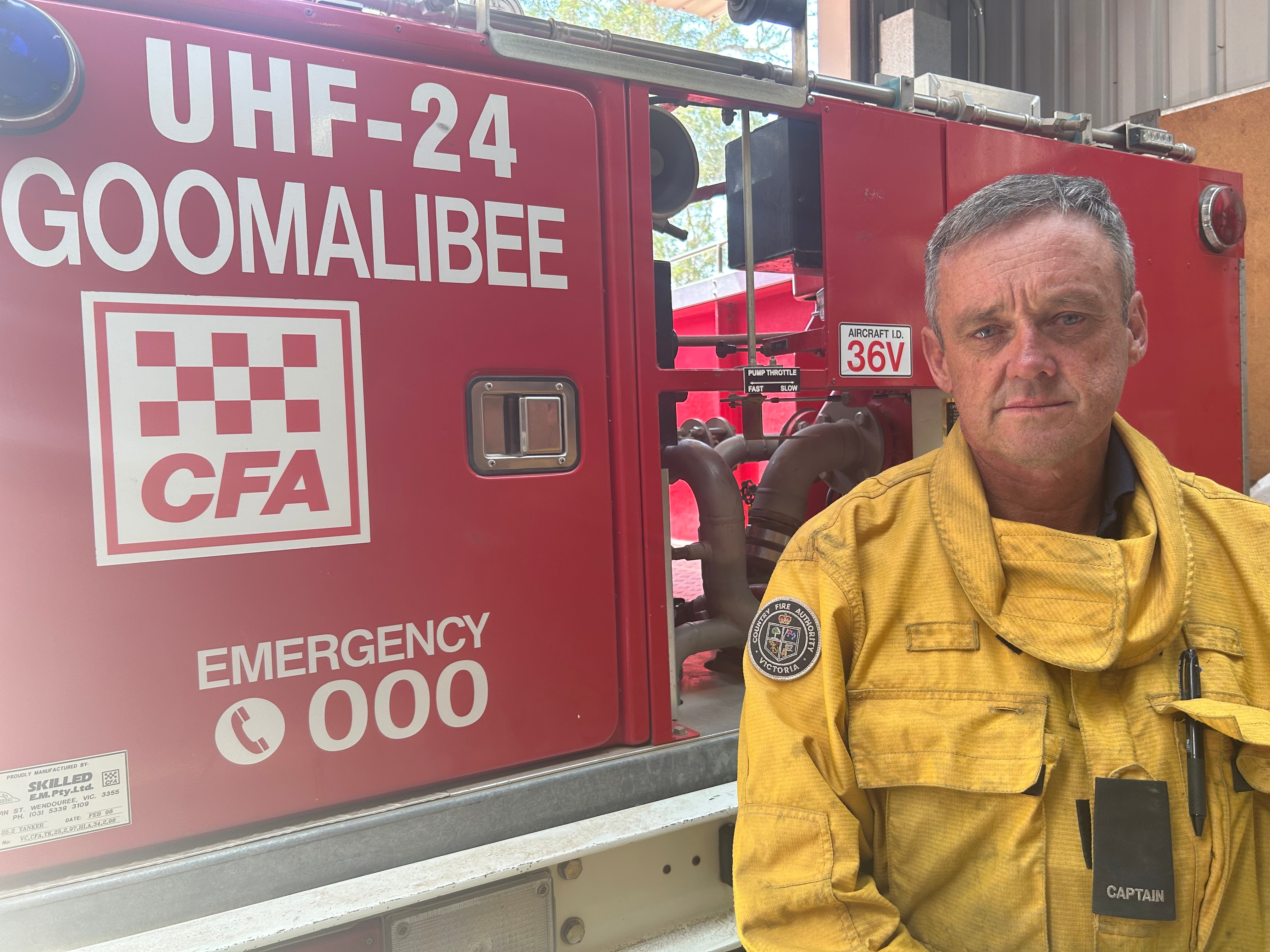 Un hombre vestido de amarillo CFA se encuentra frente a un camión CFA.