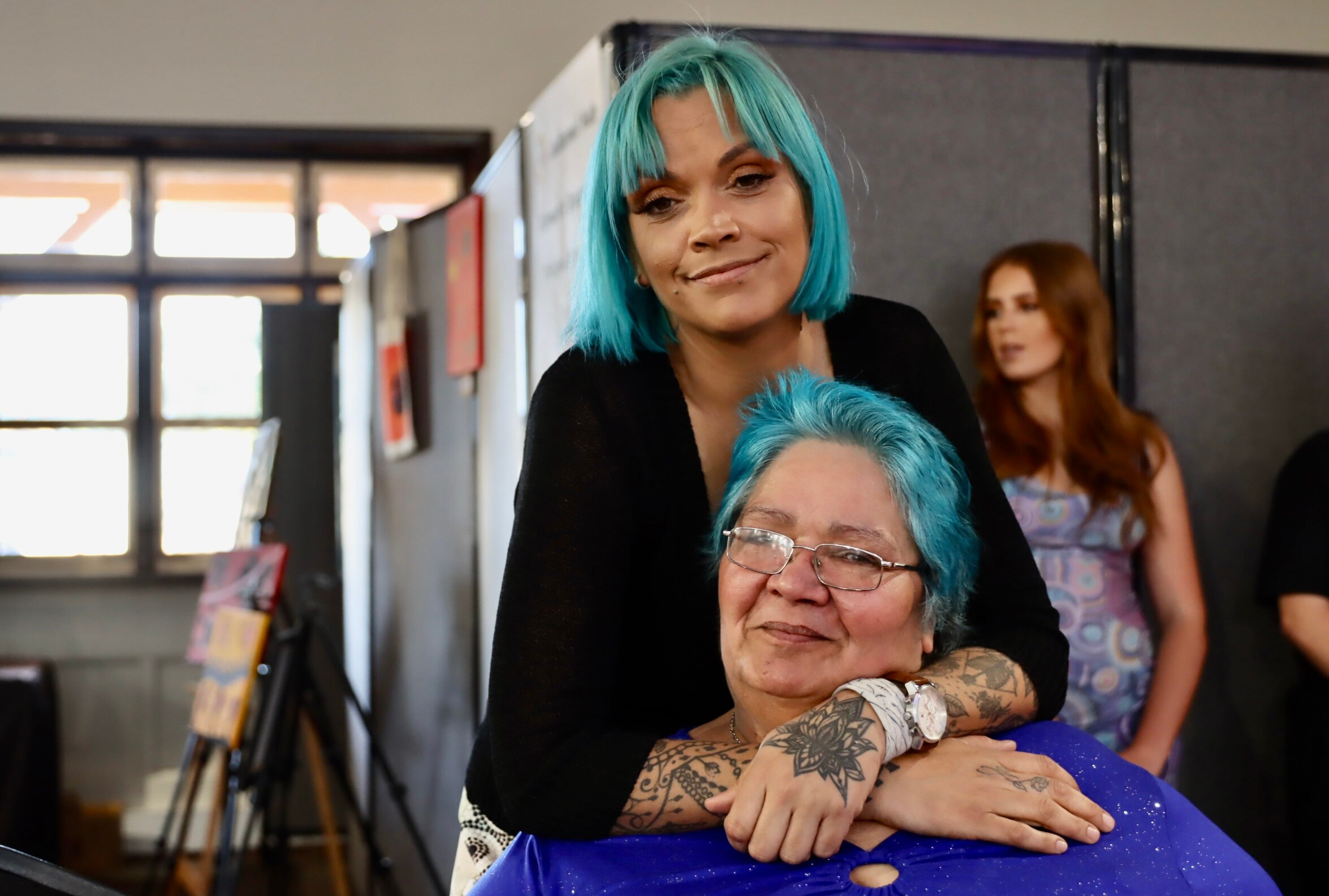 Two women with blue hair hugging 