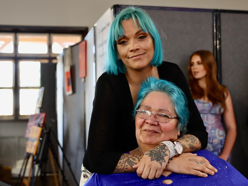 Two women with blue hair hugging 