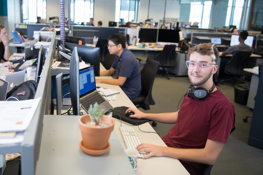 A young man sits in a computer laboratory.