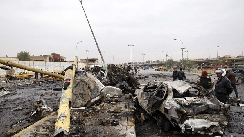 Security personnel check a burned vehicle at the site of a car bomb attack in northern Baghdad
