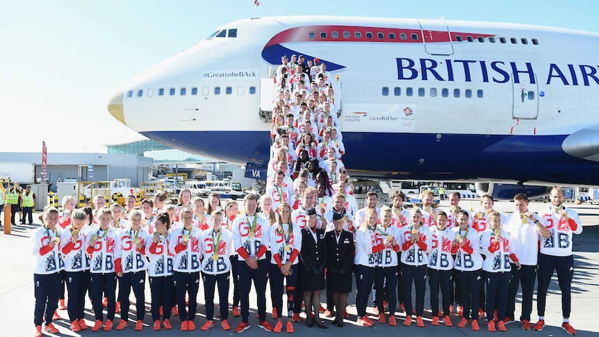 British Olympic team poses alongside gold-nosed plane