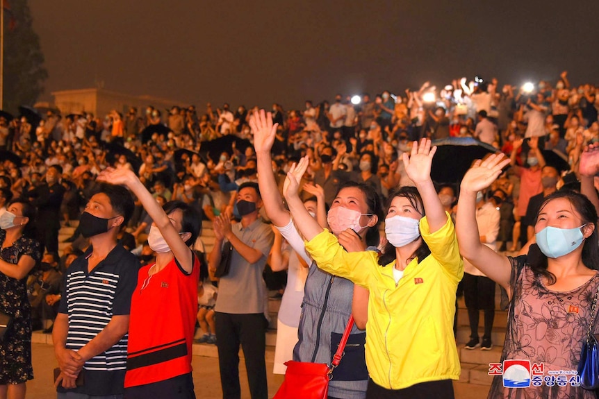 A crowd of Koreans in face masks waving