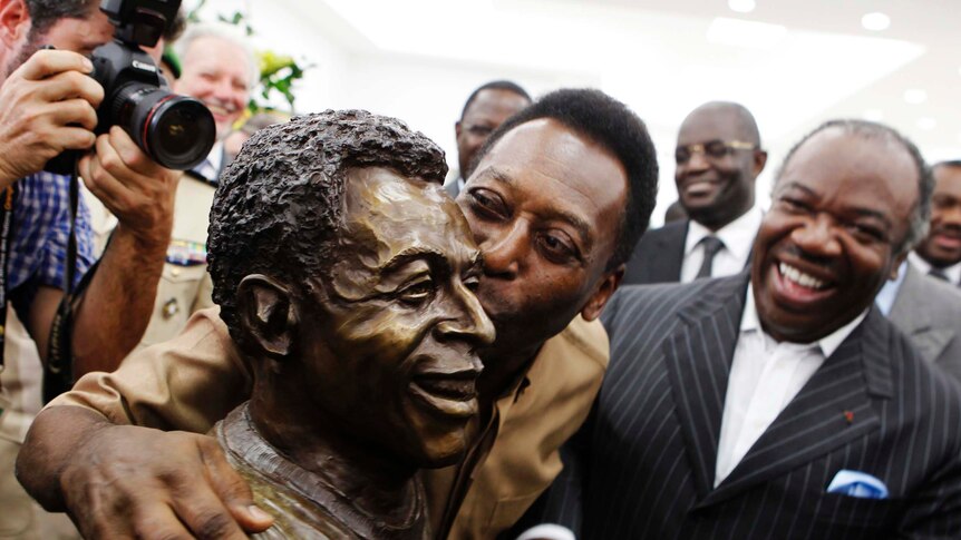 Brazil's soccer legend Pele kisses his statue in Libreville, Gabon