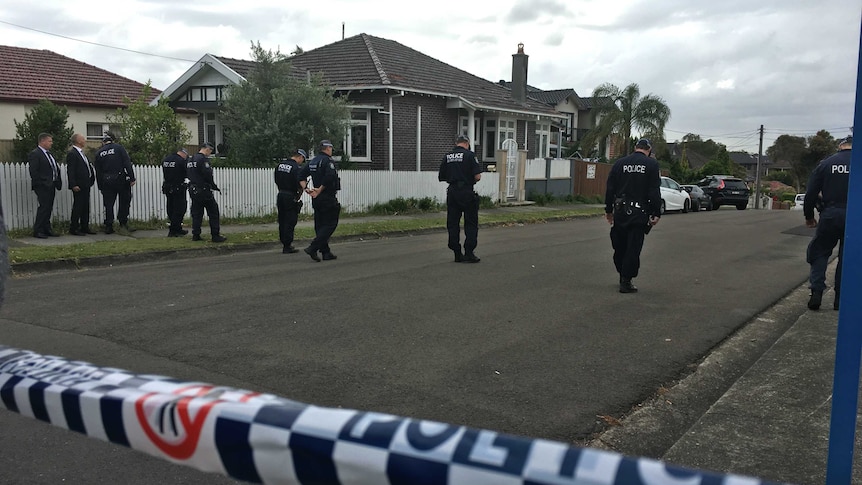 Police in a line search a road at Earlwood following a fatal shooting.