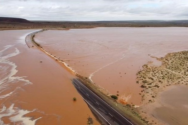 A large body of brown water sits across a highway.