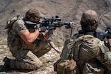 Two US Special forces soldiers with military rifles ready to fire at ISIS forces in Afghanistan.