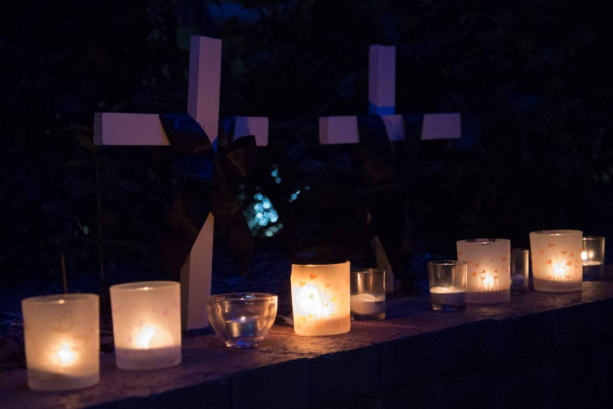 Candles and crosses in memory of victims of domestic and family violence.