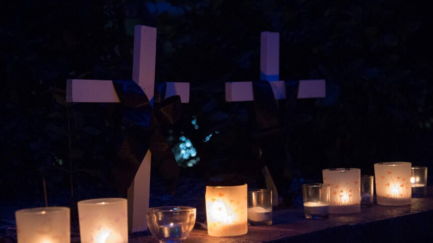 Candles and crosses in memory of victims of domestic and family violence.
