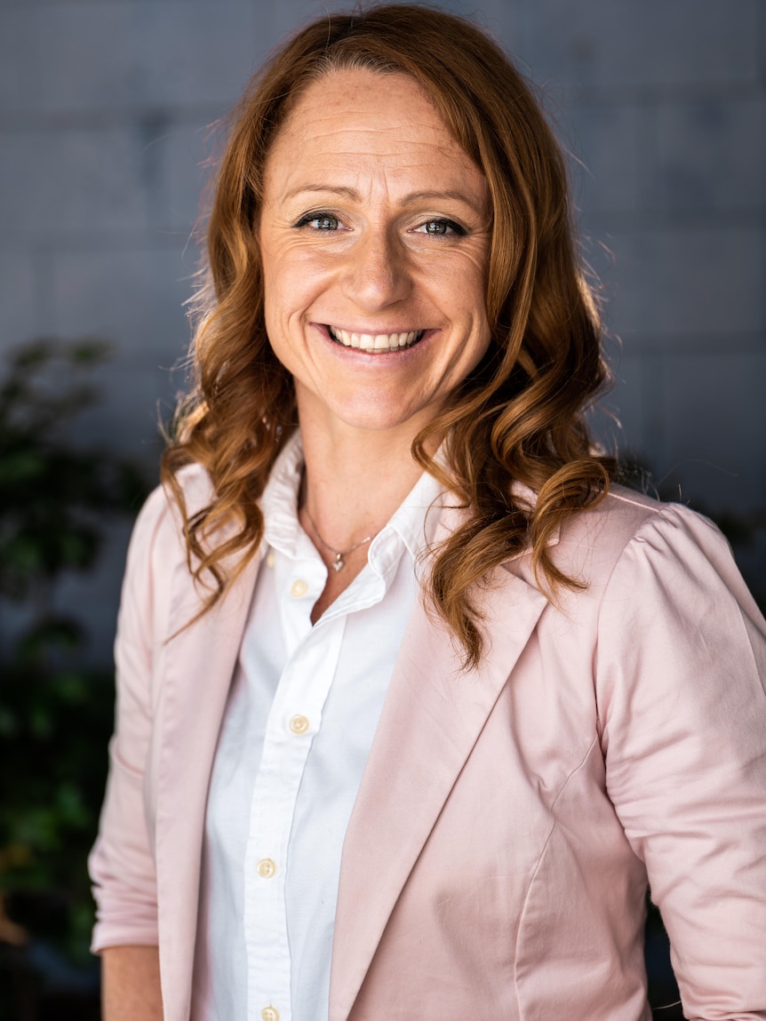 A woman in a rosa jacket with red hair.