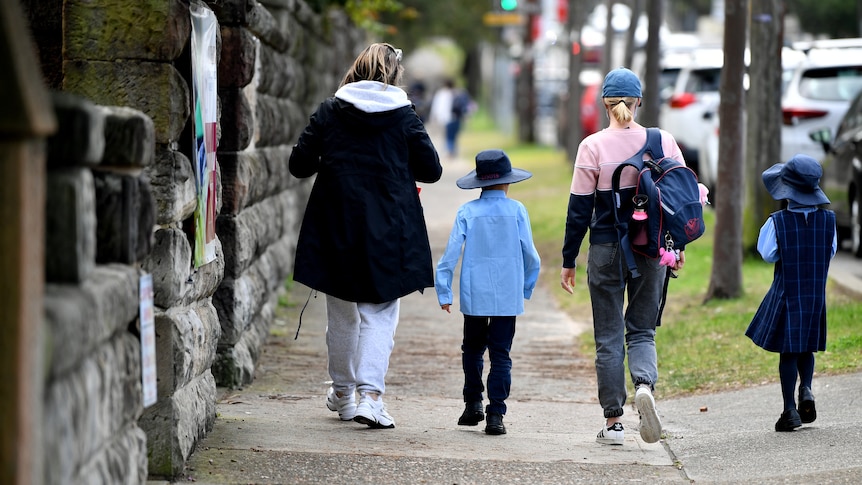 two school children walking with two women