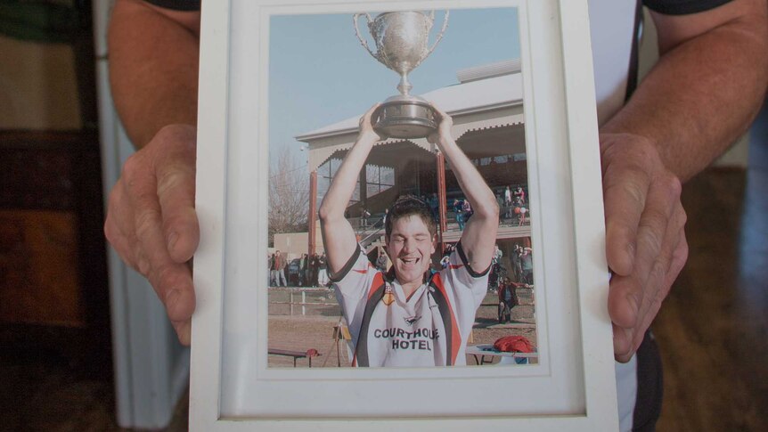 Scott Fittler holds a framed photo of his deceased brother, Jeremy