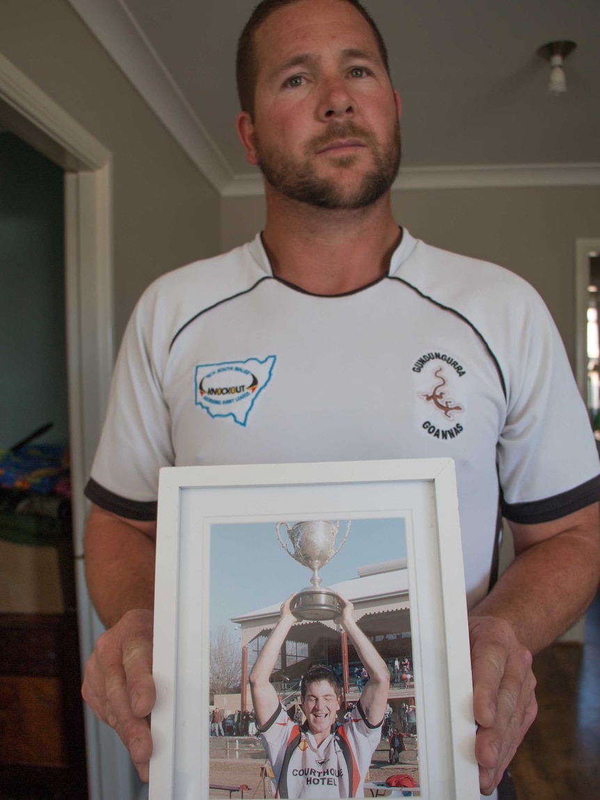 Scott Fittler holds a framed photo of his deceased brother, Jeremy