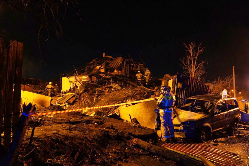 Пожарные работают среди обломков российского военного самолета в жилом доме.