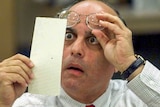 A man pulls his glasses up to inspect a ballot