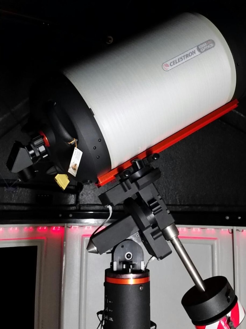 A black pole inside an observatory holds the weight of a large, tube-like, white casing which contains the lens.