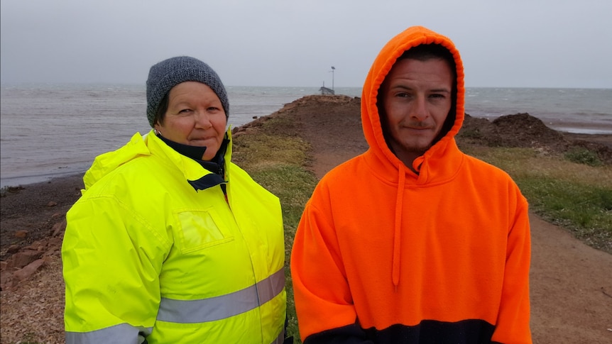 Two South Australians in high visibility clothing pose for a photo in front of the Port Germein jetty.