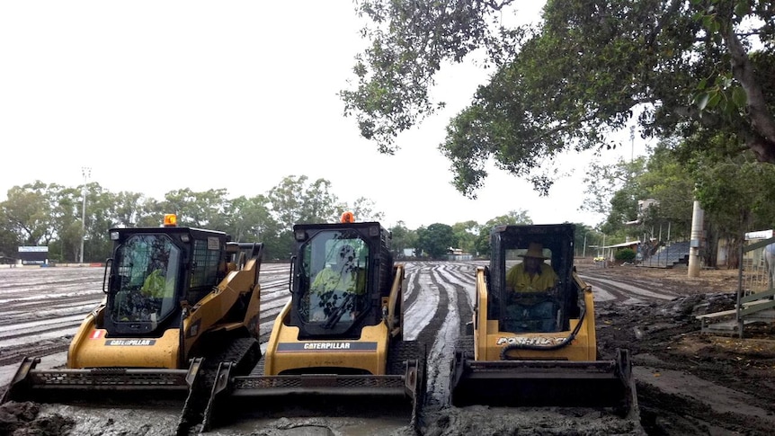 Rockhampton council staff use bob cats to scrape mud from the cricket ground.