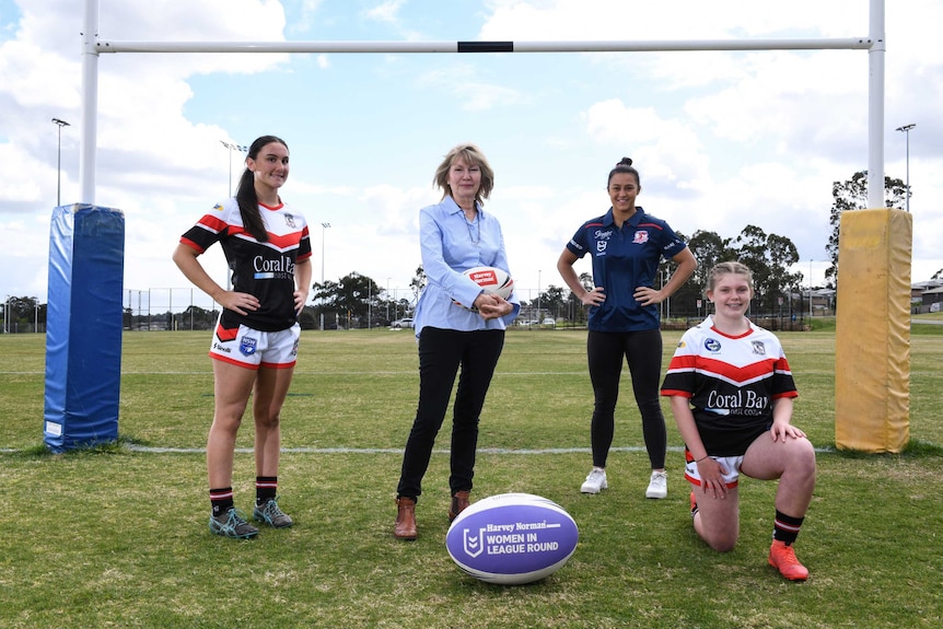 Two junior rugby players, an NRLW star and a business chief stand in front of rugby league posts.