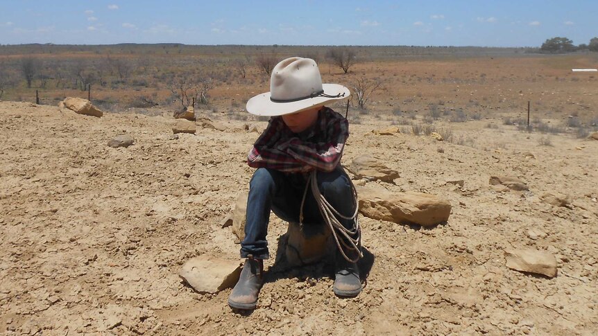 A boy sitting on drought affected land in central-west Queensland