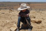 A boy sitting on drought affected land in central-west Queensland